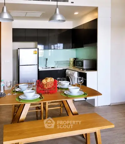 Modern kitchen with dining area, featuring sleek appliances and stylish wooden furniture.