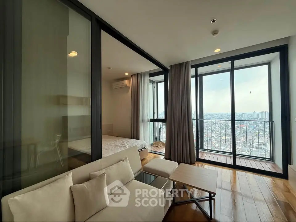 Modern living room with city view, featuring sleek furniture and floor-to-ceiling windows.