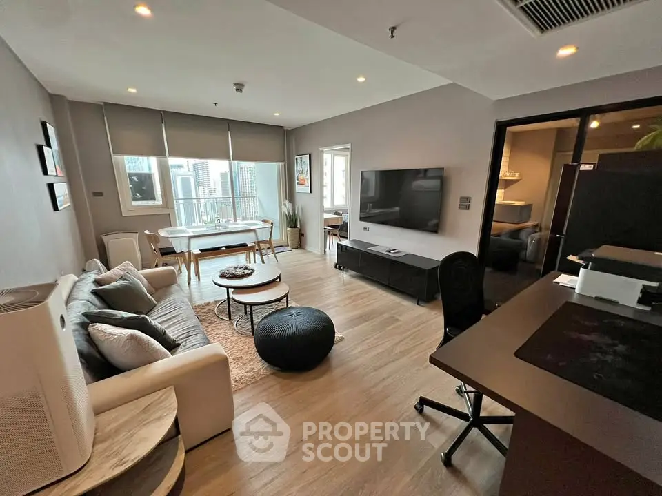 Modern living room with stylish decor and city view, featuring a cozy seating area and work desk.
