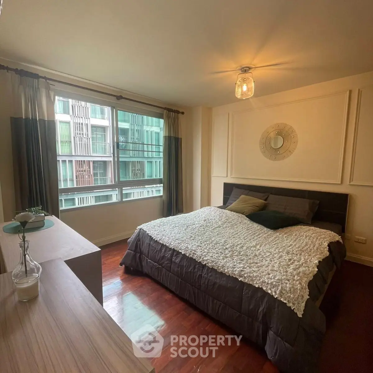 Spacious bedroom with large window and modern decor in urban apartment