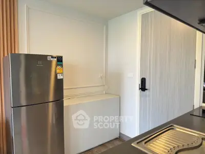 Modern kitchen with stainless steel fridge and sleek cabinetry in a contemporary apartment.