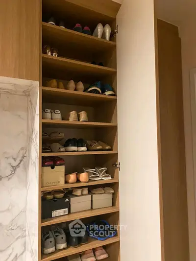 Spacious shoe storage cabinet with wooden shelves and marble accent wall