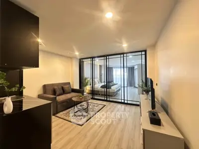 Modern open-plan living room with stylish glass partition and cozy decor