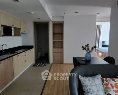 Modern open-layout apartment with sleek kitchen and cozy living area, featuring stylish decor and natural light.