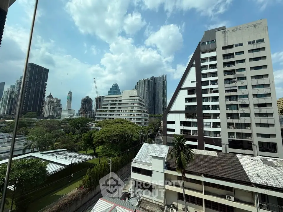 Stunning cityscape view from a high-rise building showcasing modern architecture and lush greenery.