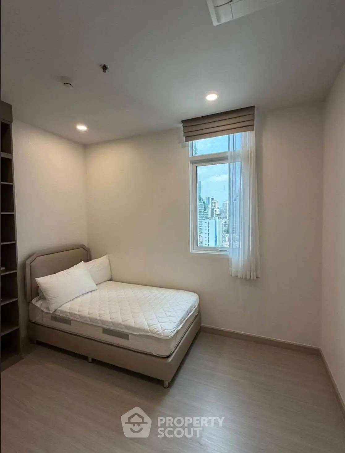 Cozy bedroom with city view, featuring a comfortable bed and ample natural light.