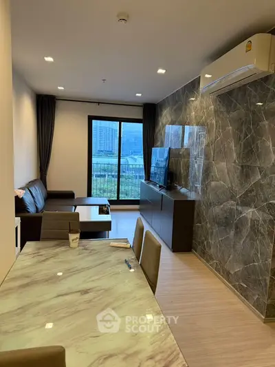 Modern living room with marble wall, sleek furniture, and city view balcony.