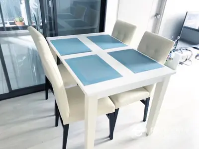 Modern dining area with sleek white table and beige chairs in bright apartment.