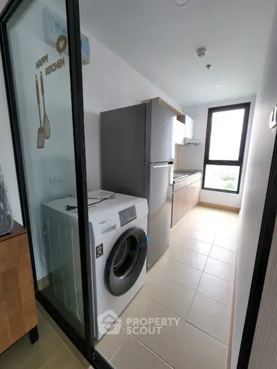 Modern kitchen with washing machine and fridge in sleek apartment