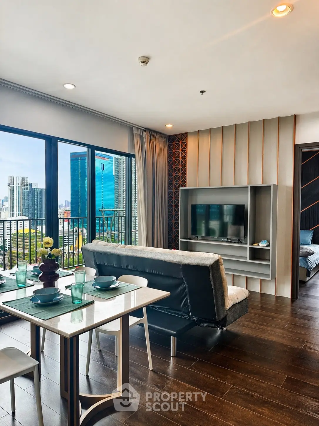 Modern living room with city view, stylish decor, and open layout in high-rise apartment.