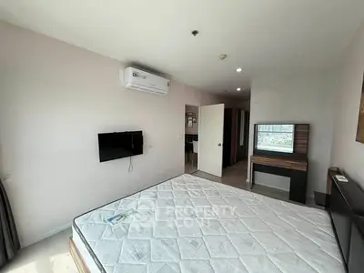 Spacious bedroom with modern furnishings and wall-mounted TV in a bright apartment.