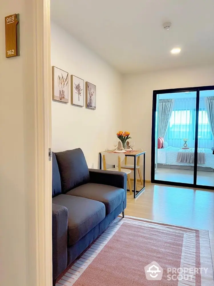 Modern living room with cozy sofa and stylish decor leading to a bright bedroom.