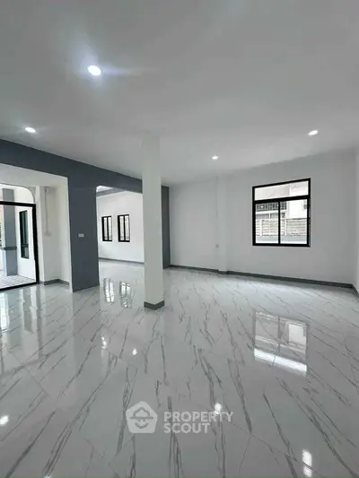 Spacious modern living area with glossy marble flooring and ample natural light.