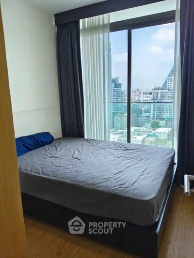 Modern bedroom with large window offering stunning city view in high-rise apartment