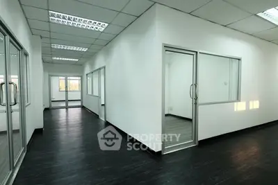 Spacious modern office space with glass partitions and dark flooring