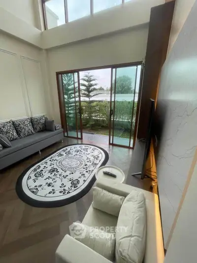 Luxurious living room with high ceiling and garden view, featuring elegant decor and modern furniture.