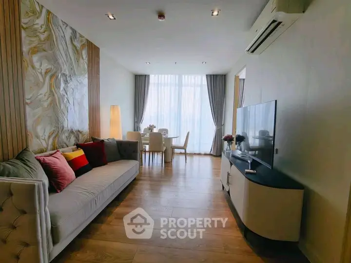 Elegant living room with modern decor and dining area, featuring stylish furniture and natural light.