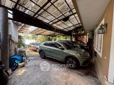 Spacious covered parking area with two cars and rustic roofing, ideal for vehicle protection.