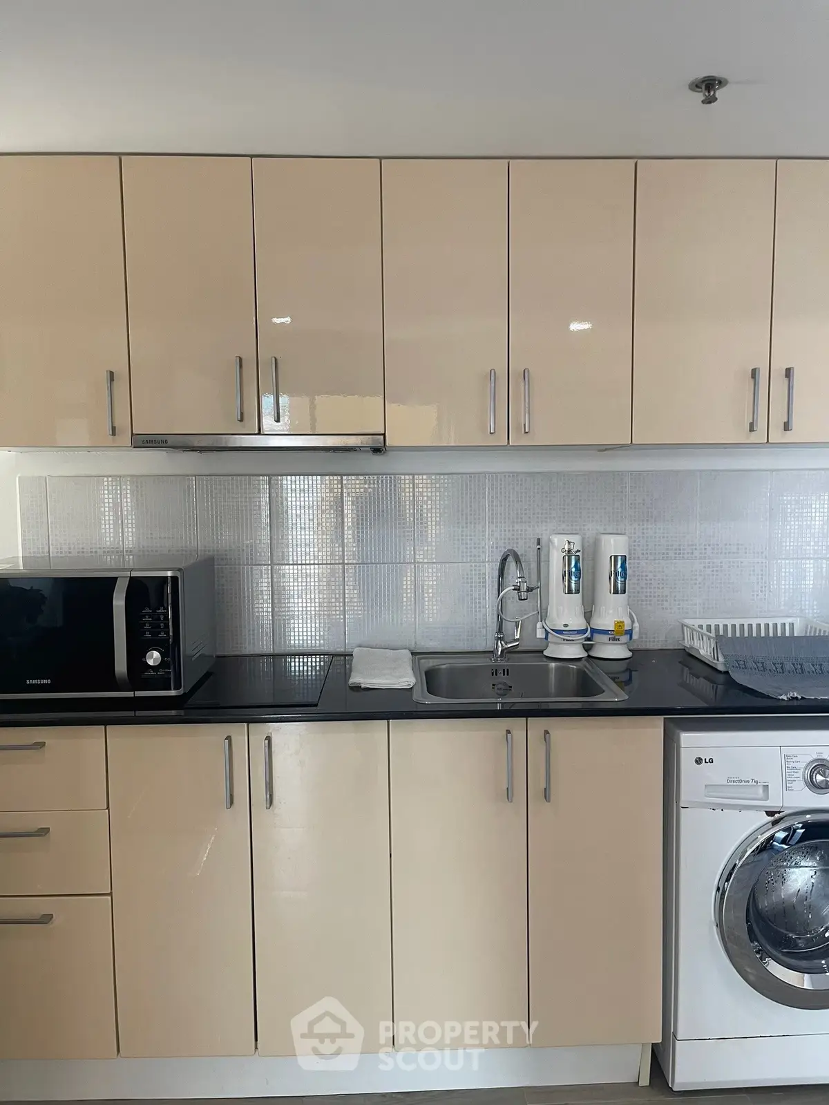 Modern kitchen with sleek cabinets, microwave, and washing machine in a compact layout.