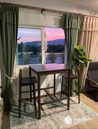 Charming dining nook with scenic sunset view and elegant green curtains