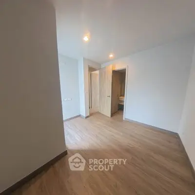 Spacious empty room with wooden flooring and modern lighting, ideal for customization.