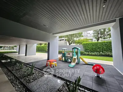 Modern residential building with children's playground and landscaped garden area.