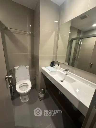 Modern bathroom with sleek fixtures and large mirror in a contemporary apartment.