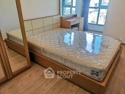 Spacious bedroom with large bed and city view window, ideal for comfort and relaxation.