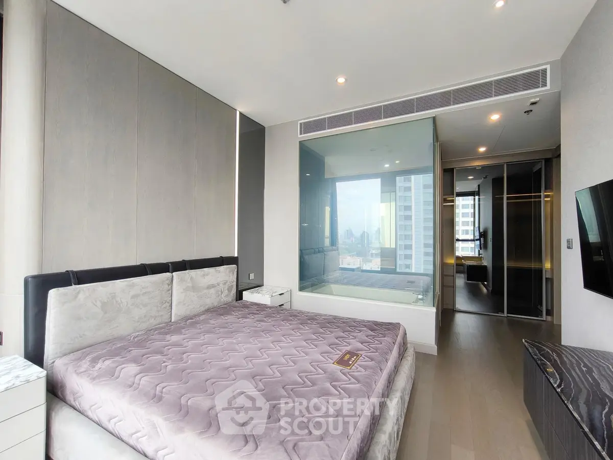 Luxurious bedroom with modern design and city view, featuring a glass-enclosed bathtub.
