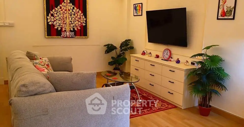 Cozy living room with modern decor, plush sofa, and wall-mounted TV, perfect for relaxation and entertainment.