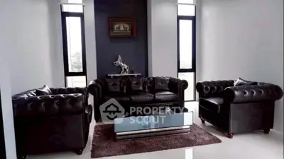 Luxurious living room with elegant black leather sofas and modern glass coffee table.