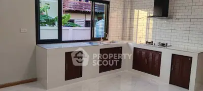 Modern kitchen with sleek cabinets and gas stove, featuring a bright open layout and large window.