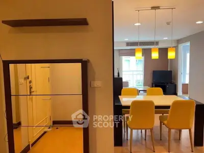 Modern dining area with yellow chairs and stylish lighting in open-plan apartment.
