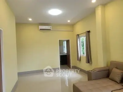 Spacious living room with modern sofa and air conditioning, featuring bright walls and natural light.