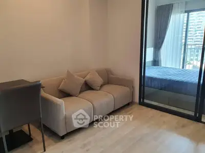 Modern apartment with cozy living room and bedroom view, featuring sleek furniture and large windows.