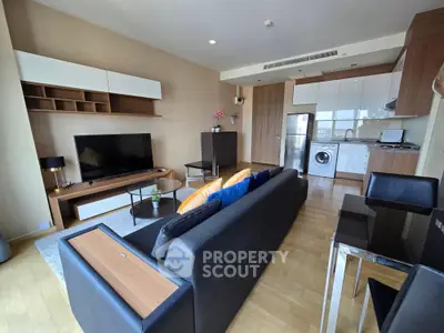 Spacious modern living room with open kitchen, featuring sleek furniture and appliances, ideal for urban living.