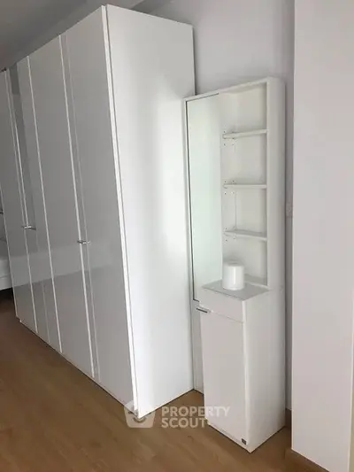 Modern white wardrobe with sleek design in a minimalist bedroom setting.