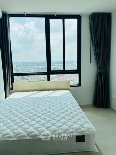 Bright bedroom with large window offering stunning city view and natural light.