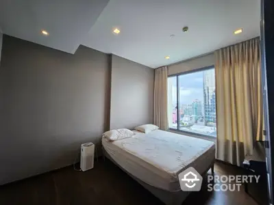 Modern bedroom with city view and large window in high-rise apartment