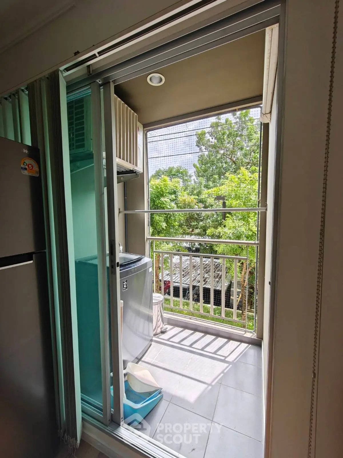 Charming balcony with lush green view and modern washing machine setup.