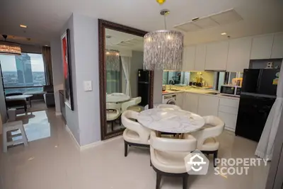 Elegant dining space with modern chandelier, adjacent to a sleek kitchen with top-notch appliances and a cozy living area.