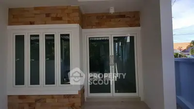 Modern home exterior with large windows and sliding glass door, showcasing contemporary design.