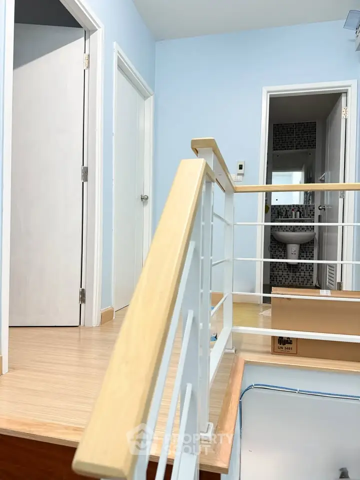 Modern interior hallway with wooden railing and bathroom view