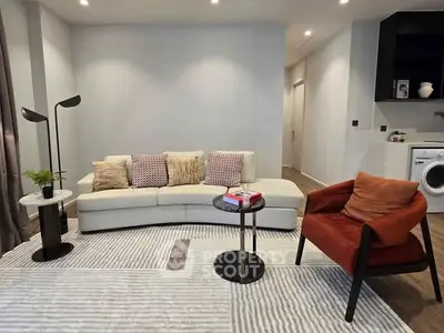Modern living room with stylish furniture and washing machine in open layout.