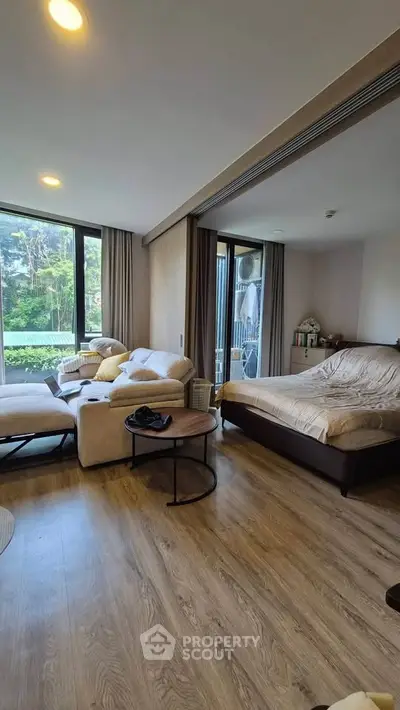 Spacious living room with large windows and cozy seating area in modern apartment.