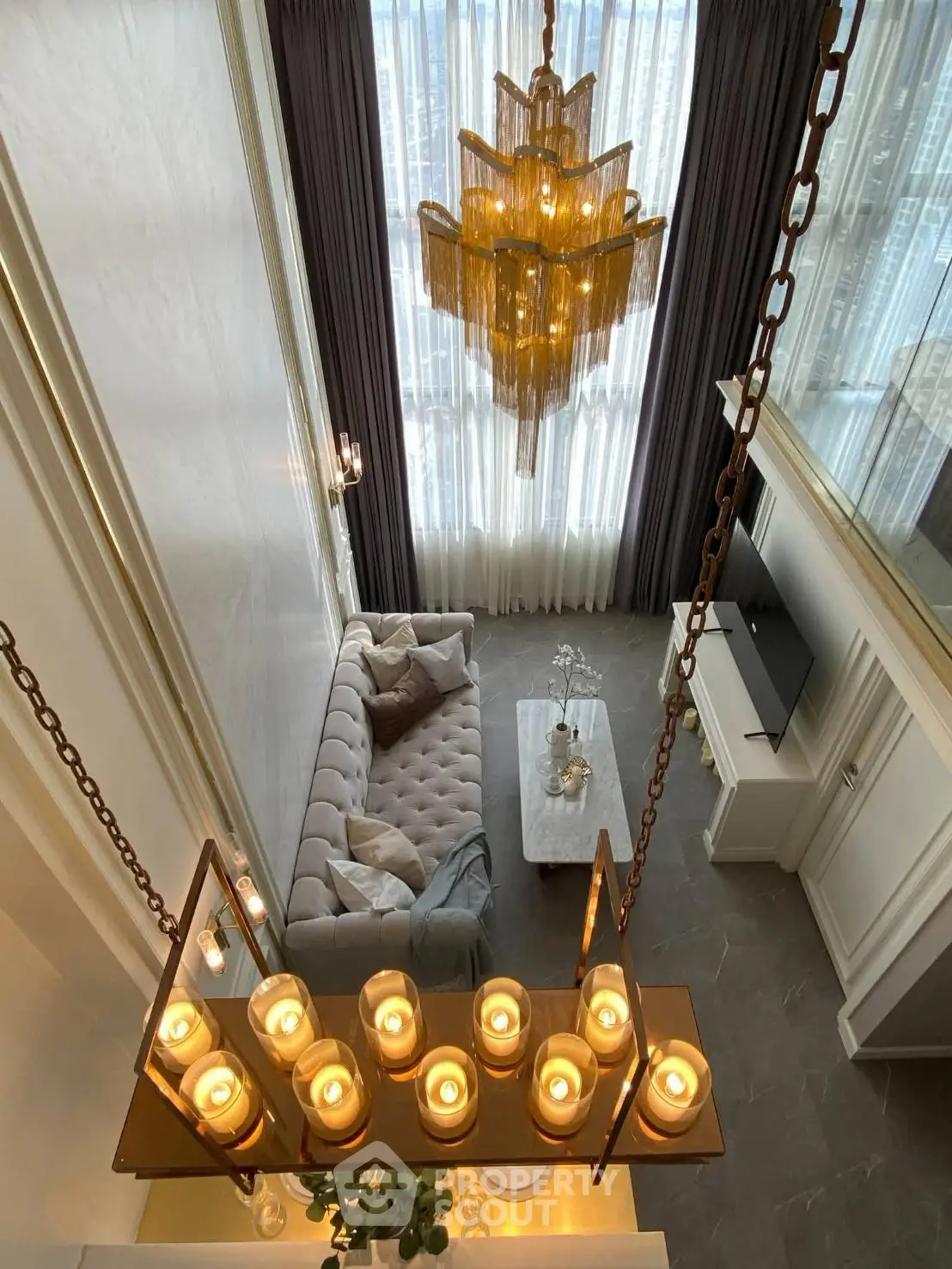 Luxurious high-ceiling living room with elegant chandelier and plush sofa in modern apartment.