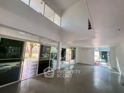 Spacious modern living room with large windows and high ceilings, offering abundant natural light and garden views.