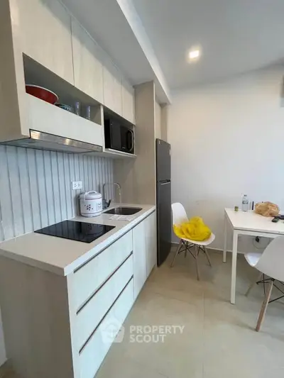 Modern kitchen with sleek cabinetry and dining area in a contemporary apartment.