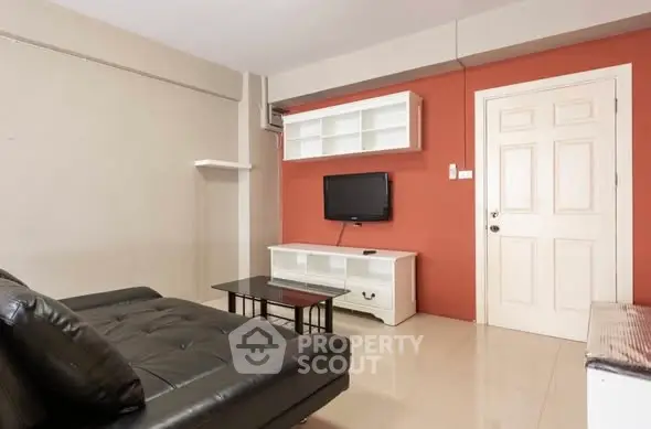 Modern living room with sleek black sofa, wall-mounted TV, and stylish shelving unit.