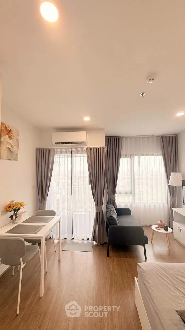 Modern living room with cozy seating and dining area, featuring large windows and stylish decor.